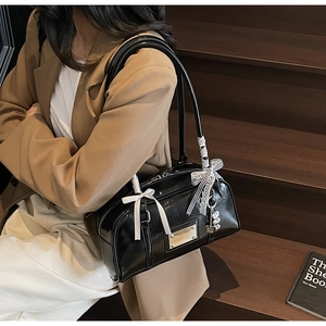 Chic black patent leather shoulder bag with decorative bows and silver heart charm detail