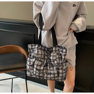 Detail of checkered tote bag featuring three functional drawstring pockets and nylon straps