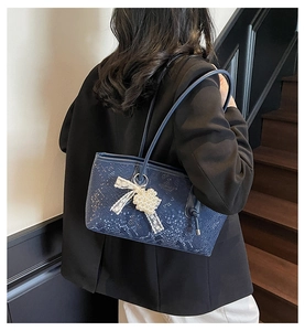 Détail du sac cabas bleu foncé avec texture crocodile et breloque noeud en perles