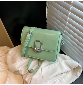 Detail of mint green leather square bag showing textured finish and silver metal clasp