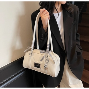 Detail of cream glossy shoulder bag with silver logo plaque and heart charm decoration