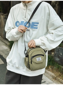 Detail of olive green waterproof nylon crossbody bag with multi-layer zipper pockets