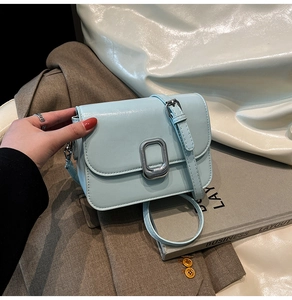 Close-up of light blue small square bag featuring a textured silver metal clasp detail