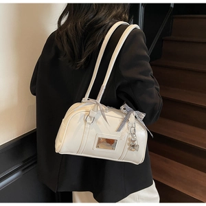 Detail of cream white faux leather shoulder bag with striped bow and silver charm