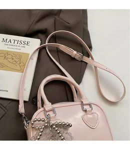 Detail of light pink boston bag featuring heart quilting and beaded decorative charm
