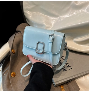 Close-up of light blue small square bag with metal buckle and thin shoulder strap