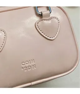 Close-up of pink leather handbag showing heart stitching and silver hardware detail