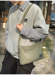 Close-up of army green nylon messenger bag featuring dual front pockets and woven strap