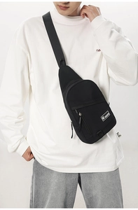 Vue détaillée du sac bandoulière en toile noire avec étiquette blanche et sangle réglable