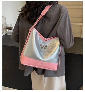 Detail of silver pleated tote bag featuring a metallic bow and pink shoulder strap