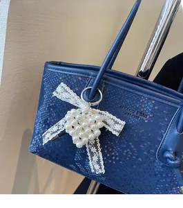 Detail of dark blue faux python tote bag with pearl heart lace charm and logo