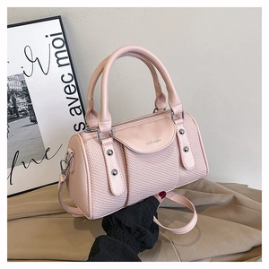 Detail of pink cylindrical handbag featuring woven texture and silver rivet accents