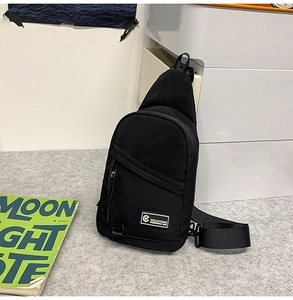 Détail du sac de poitrine en nylon noir avec poche zippée et écusson logo de marque blanc