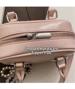 Detail of pink faux leather handbag showing smooth silver metal zipper and pearl charm