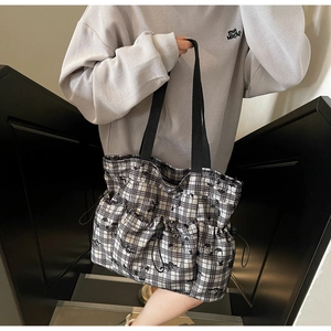 Detail view of large checkered tote bag with side drawstring and spacious front pocket