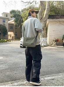 Outdoor shot of army green nylon crossbody bag showing back view on a city street