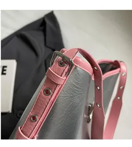 Close-up of silver cracked texture underarm bag with pink leather strap and metal buckles