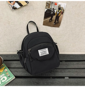 Close-up of black nylon shoulder bag featuring the CHUANGMI woven label and front zipper