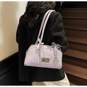 Close-up of lavender shoulder bag with satin bows and heart-shaped metal pendant
