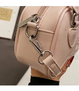 Detail of silver-tone metal hook and zipper on a light pink leather crossbody pillow bag
