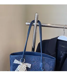Detail view of navy blue snakeskin embossed tote bag with pearl lace bow charm