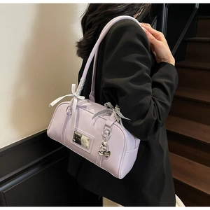 Detail of lavender shoulder bag featuring decorative white and checkered bows and heart charm