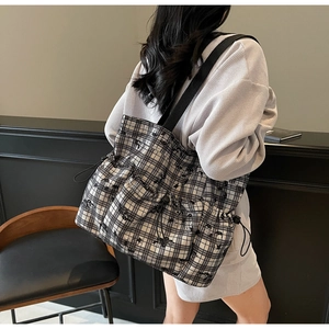 Detail of checkered canvas tote bag with drawstring pockets and adjustable black shoulder strap