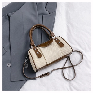 Detailed shot of two-tone woven Boston bag with brown leather trim and metal rivets