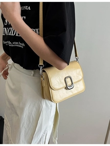 Pale yellow minimalist square crossbody bag with metallic lock shown on model shoulder