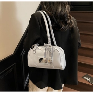 Detail of light blue patent leather shoulder bag featuring a silk scarf and heart pendant