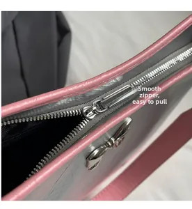 Macro detail of smooth silver metal zipper and bow charm on a stylish underarm bag