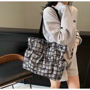 Detail of checkered tote bag featuring a Snoopy cartoon and drawstring side pockets