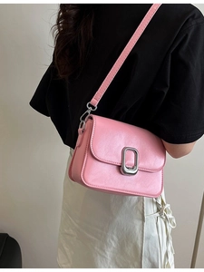 Pink faux leather crossbody bag with silver buckle worn by a model on the shoulder