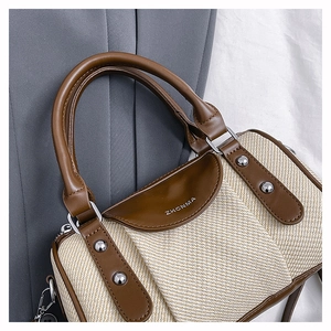 Detail of color-block Boston bag featuring herringbone weave and brown leather trim