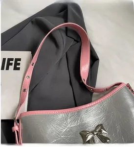 Detail of silver metallic tote bag with pink leather strap and bow decoration