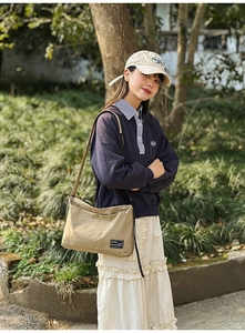Detail of khaki nylon tote bag with black woven label in a Japanese casual street style