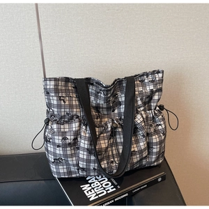 Close-up of black and white checkered tote bag featuring functional side drawstring pocket