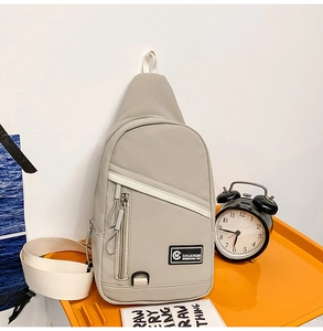 Détail du sac bandoulière en nylon gris clair avec fermeture éclair et sangle blanche