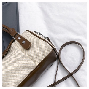 Detailed view of bicolor woven and brown leather crossbody bag with silver metal studs