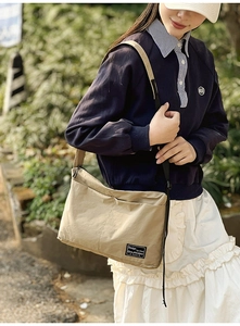 Close-up of khaki nylon crossbody bag featuring double front pockets and fabric logo label