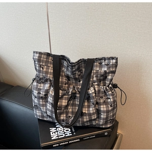 Detail of checkered canvas tote bag with cartoon print and side drawstring pocket