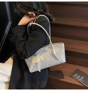 Detailed macro view of silver metallic snake pattern tote bag with pearl bow accessory