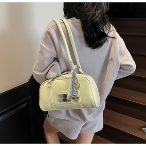 Detail of light green Boston bag with ribbon decor and heart charm on a model