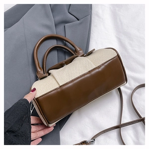 Detailed close-up of two-tone barrel bag with woven texture and premium leather handles