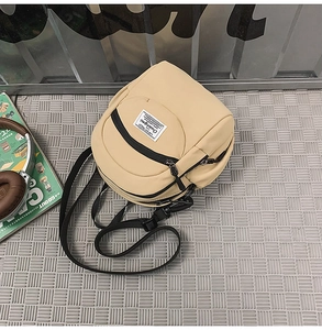 Close-up of beige nylon crossbody bag with adjustable black strap and woven label