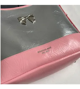 Detail of pink and silver pleated underarm bag with metal bow and brand lettering