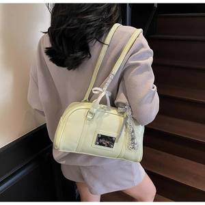 Detail of green Boston bag with silver plaque, lace heart charm and white bow decoration