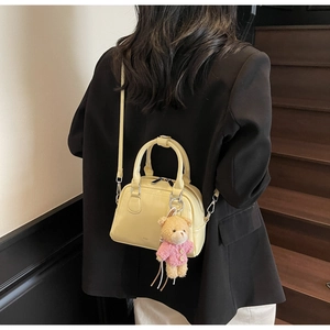 Modella che indossa mini borsa bowling gialla con ciondolo a orsetto e fibbie argento