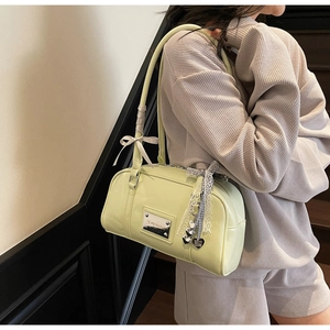 Detail view of light green Boston bag featuring lace edges and heart pendants