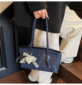 Détail du sac cabas bleu marine effet serpent avec charm nœud perlé et dentelle élégante